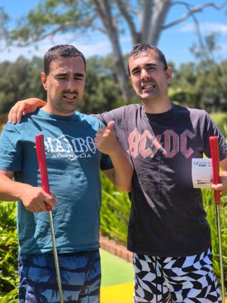 Two participants enjoying a game of mini-golf outdoors